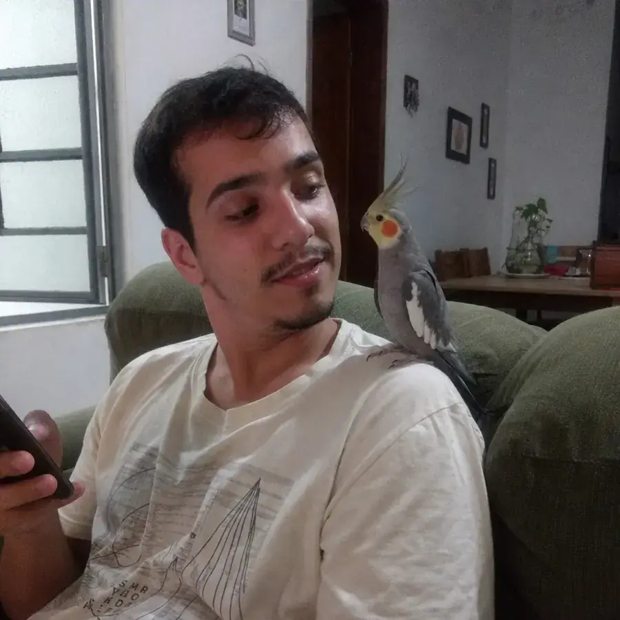 Tutor consultando o manual com a calopsita no ombro
